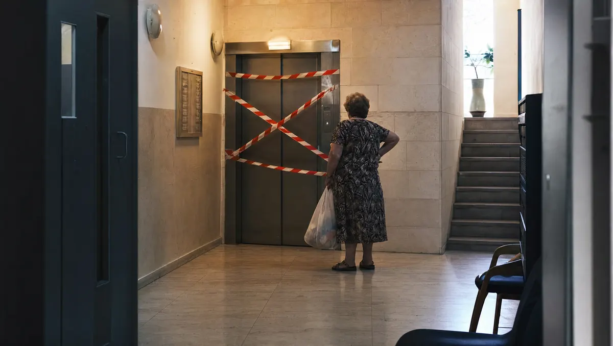 המחשה: מעלית מושבתת בסרט אזהרה בלובי בניין מגורים, דיירת ממתינה לידה